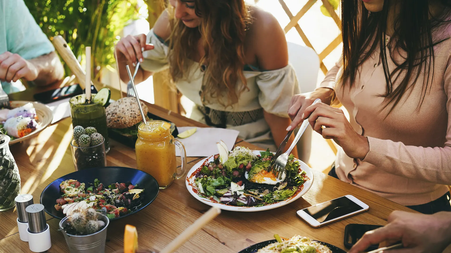 Repas d'été partagé en terrasse : salades fraîches et smoothies autour d'une table conviviale