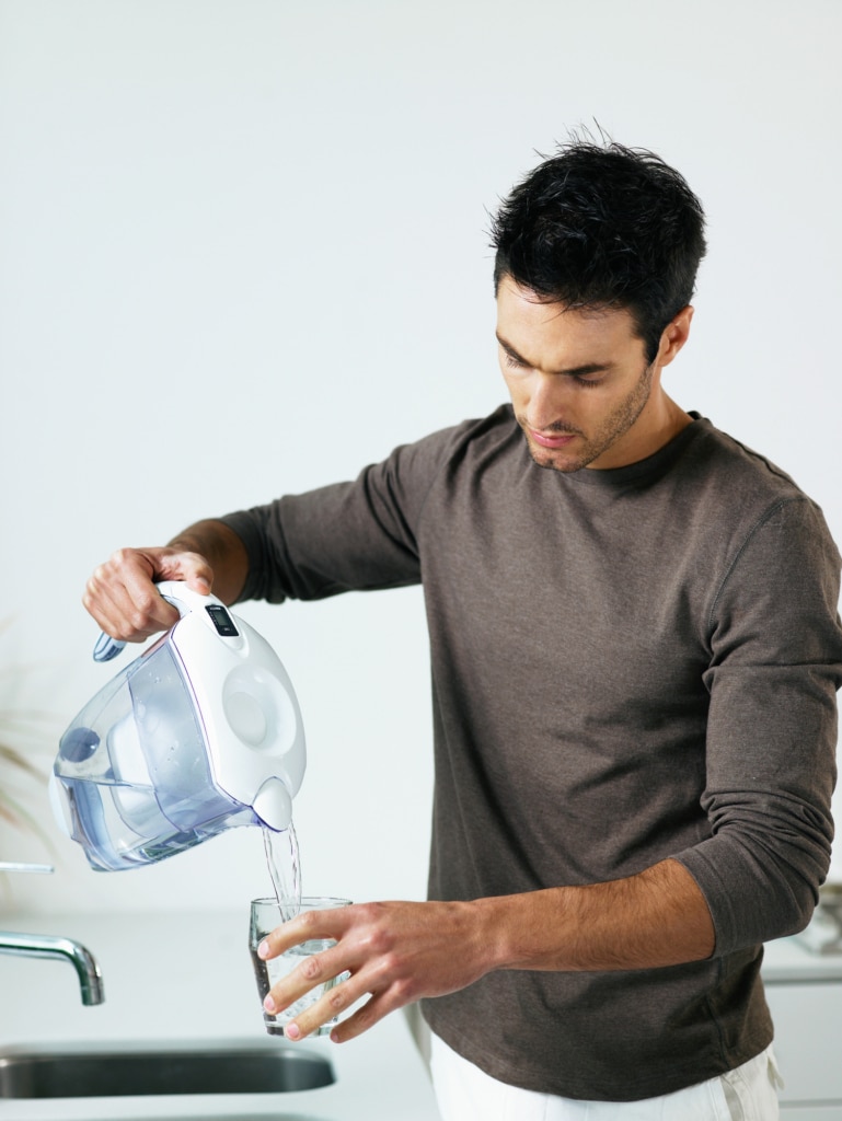 Homme versant de l'eau filtrée par sa carafe filtrante