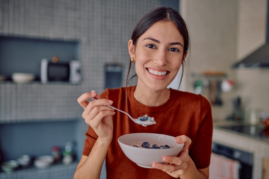 Une jeune femme déguste un petit-déjeuner sain composé de flocons d'avoine et de myrtilles.