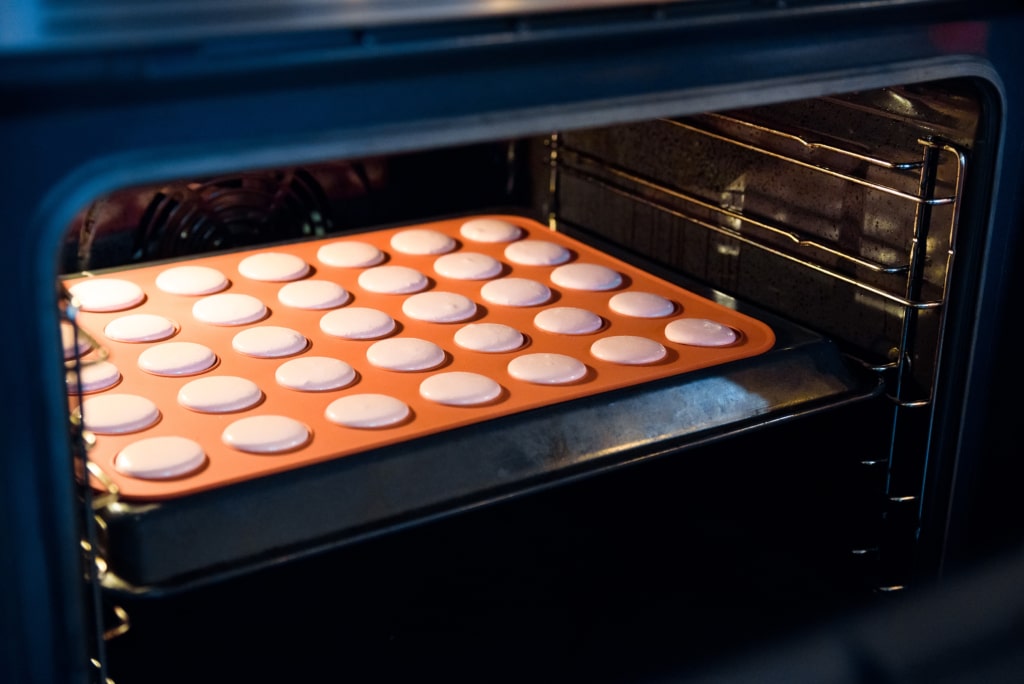 Tapis de cuisson avec&nbsp;des macarons roses français en train de cuire