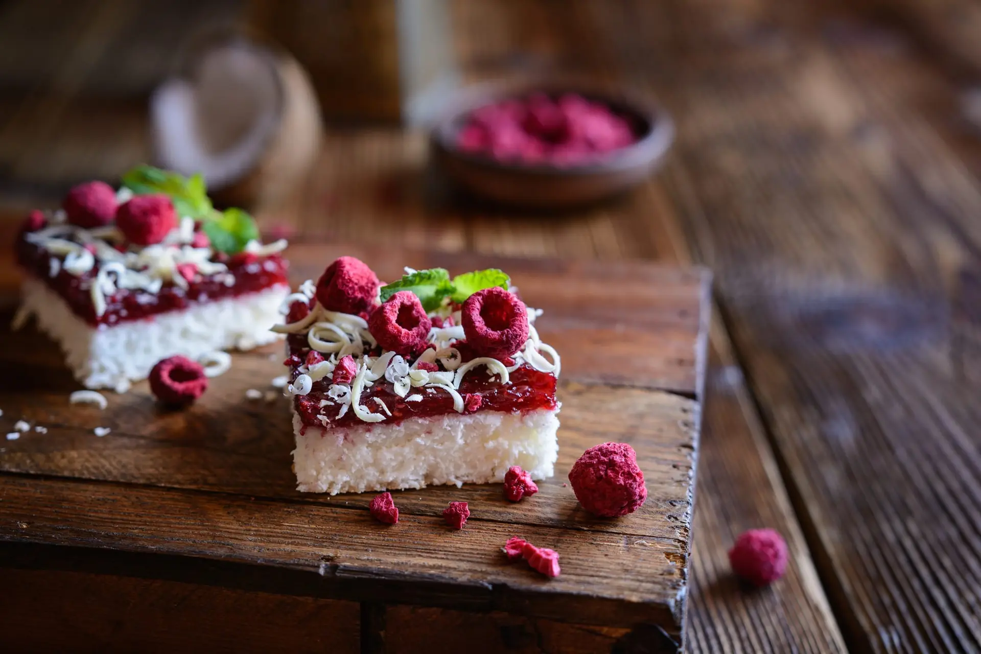 Gâteau à la noix de coco avec une couche de framboise, garni de copeaux de chocolat blanc