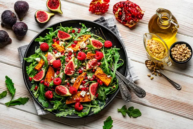 Salade de roquette avec figues, baies, des légumes cuits au four, quinoa et feta