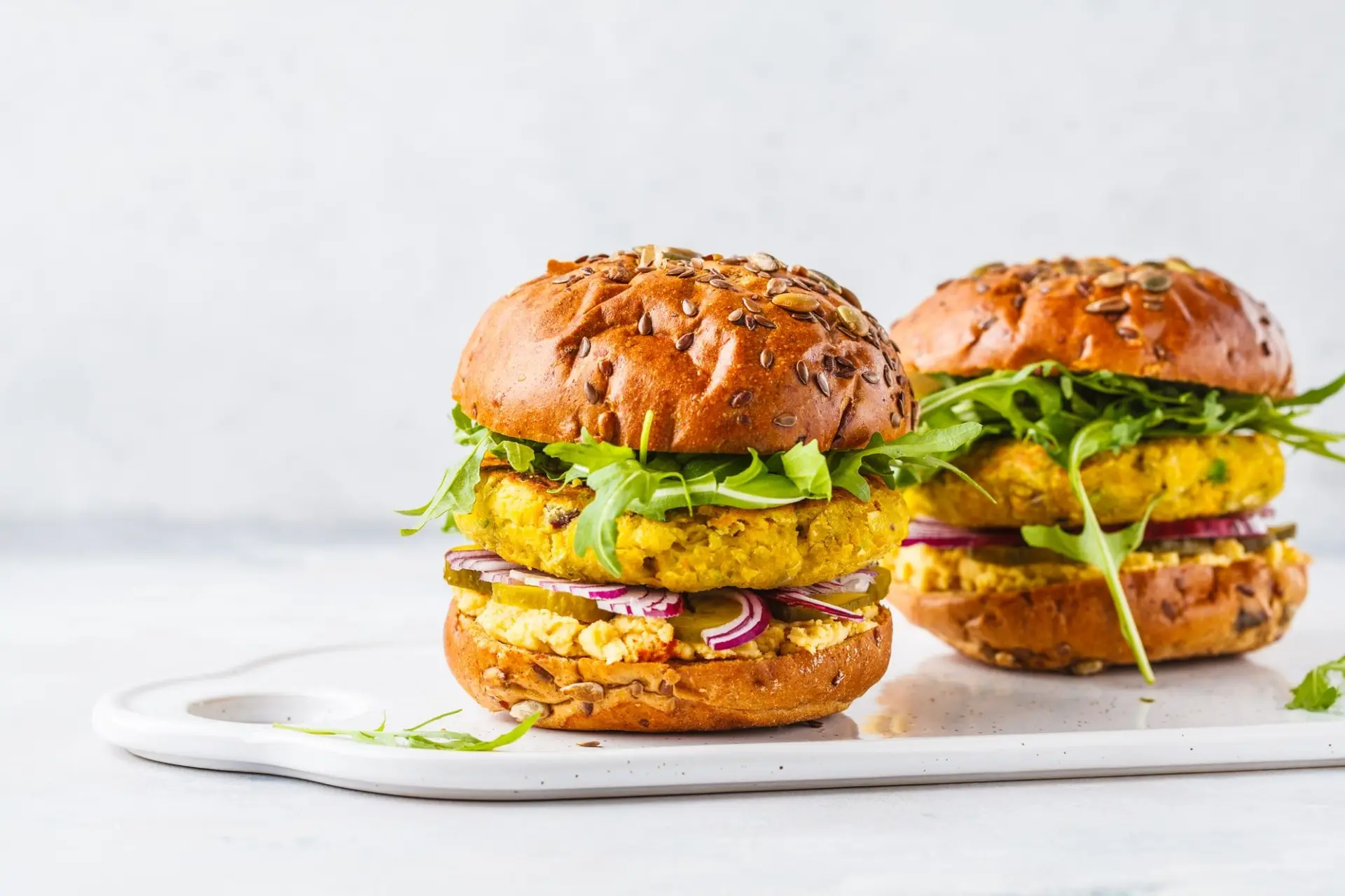 Burgers de pois chiches végétalien avec roquette, concombres marinés et houmous