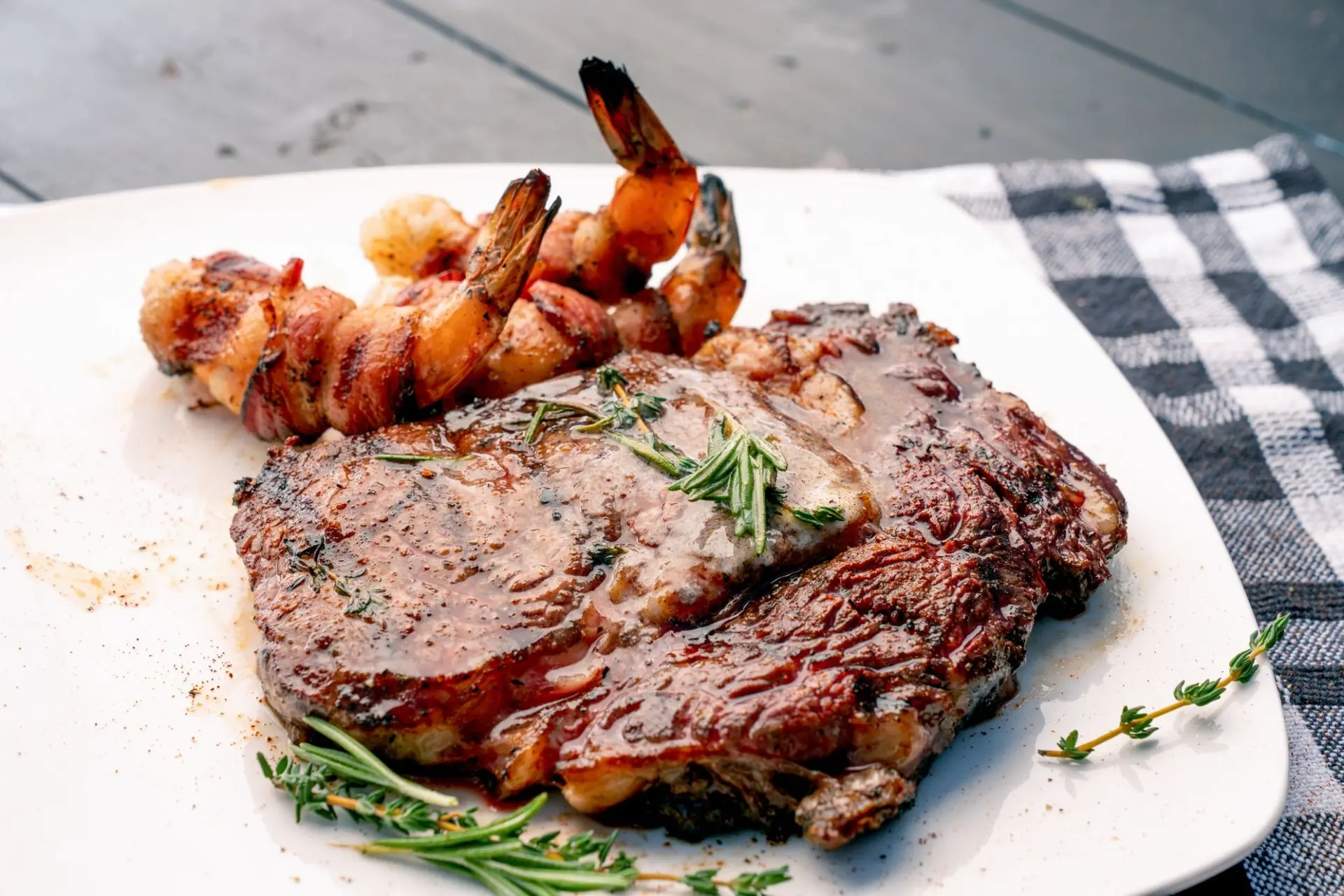 Steak de ribeye au thym et au romarin avec crevettes au bacon