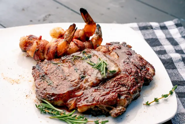 Steak de ribeye au thym et au romarin avec crevettes au bacon