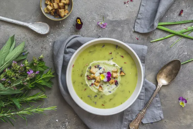 Soupe aux herbes crémeuse à l'oseille, fleurs comestibles et croutons
