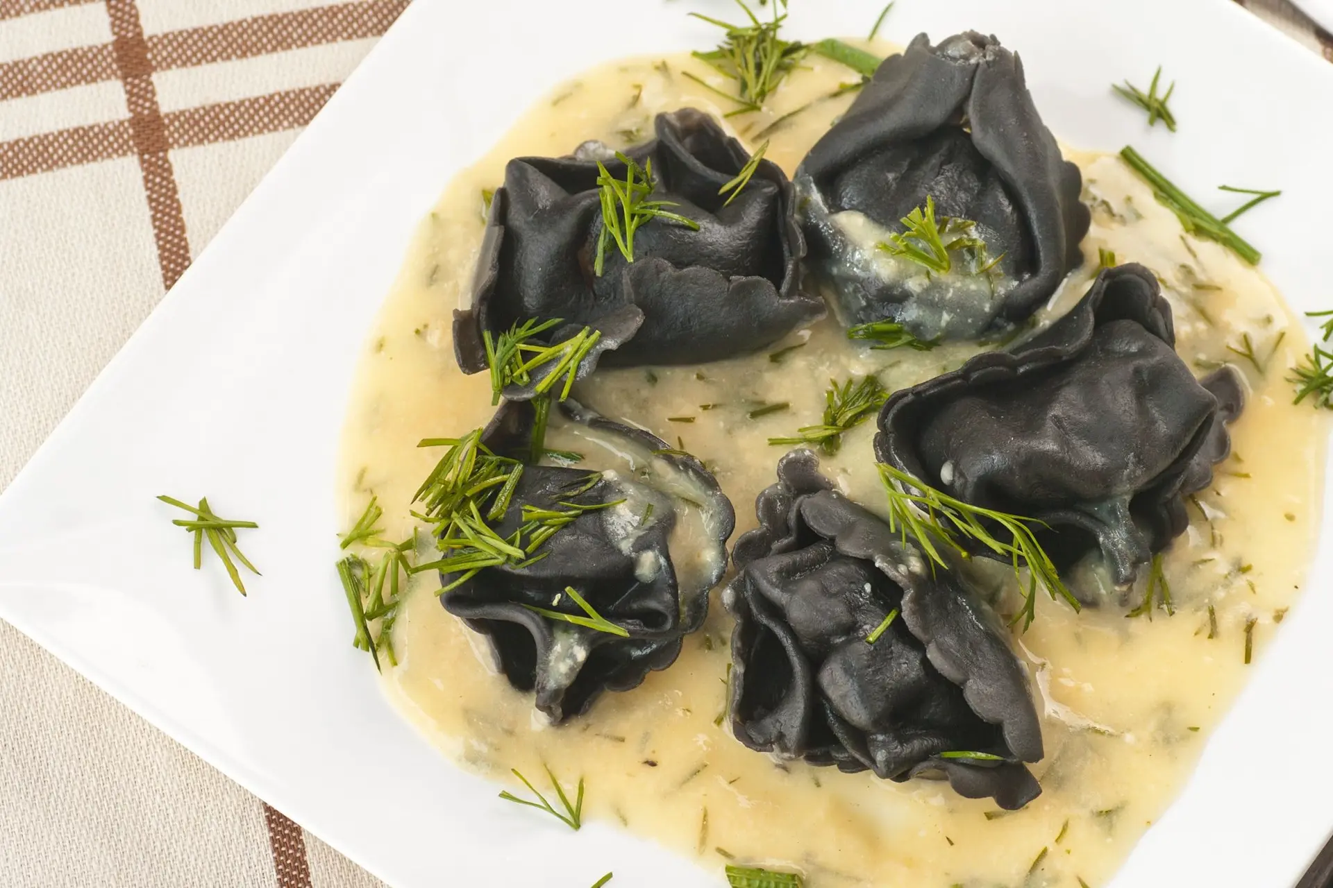 Raviolis noirs garnis de saumon à l'aneth, sauce à la moutarde